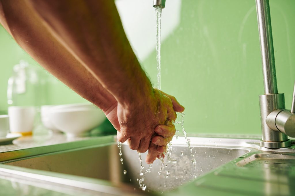 Man rinsing hands under tap water